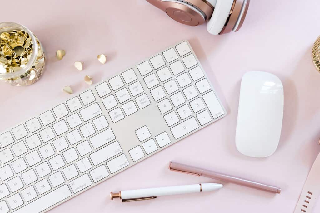 Blog keyboard next to a white mouse on a light pink background