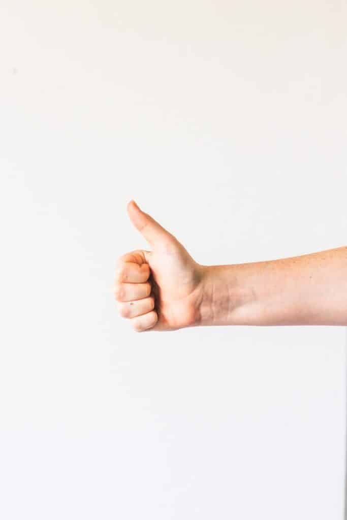 persons right hand doing thumbs up