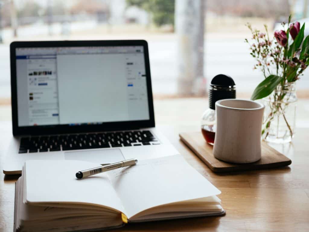 MacBook Pro near white open book as someone writes a guest post