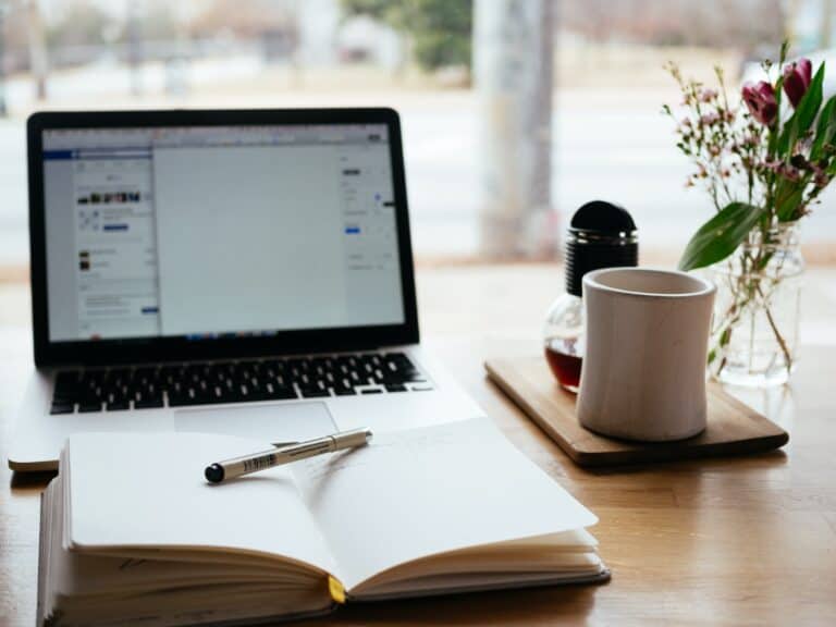 MacBook Pro near white open book as someone writes a guest post